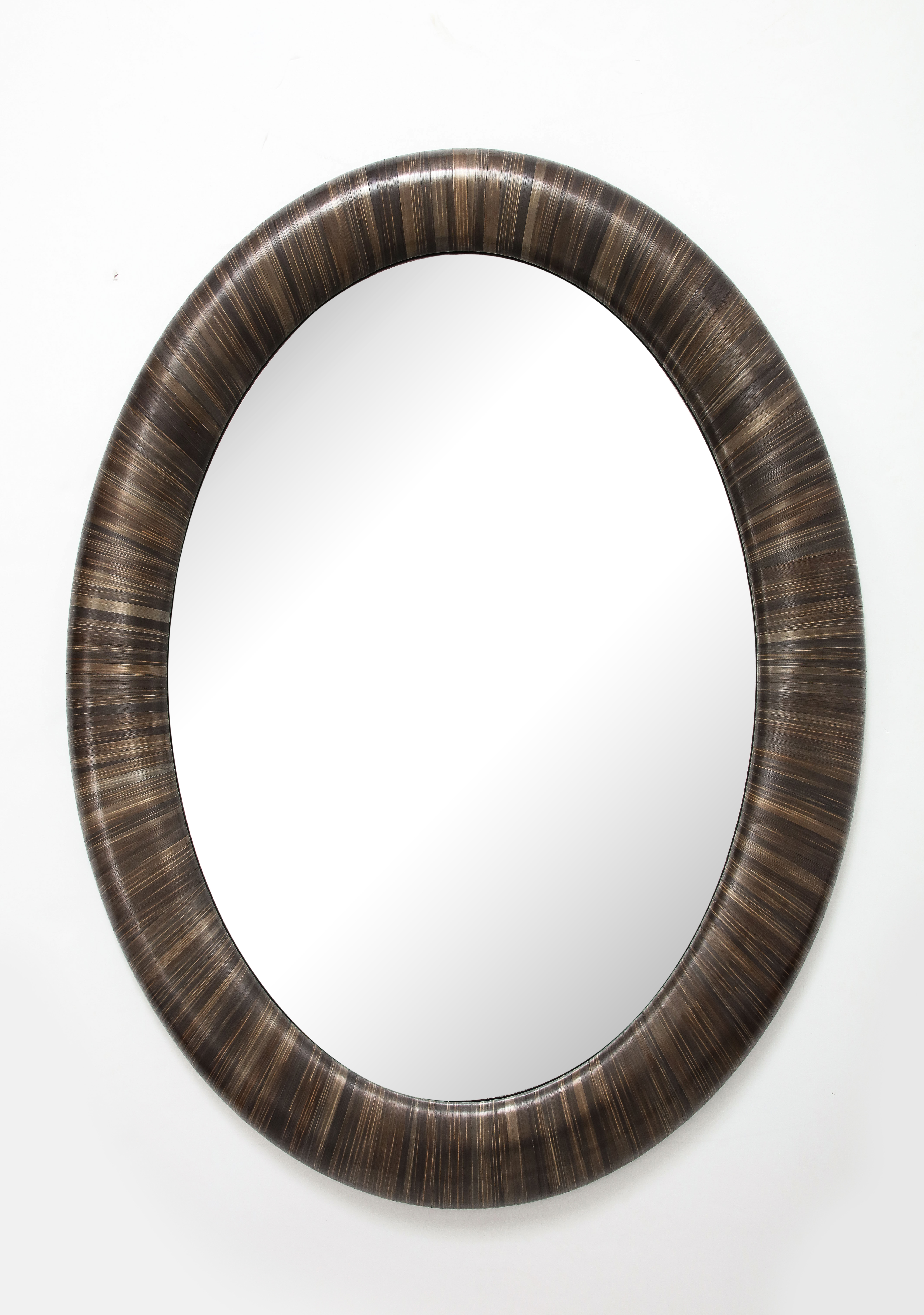 A Modernist oval mirror of contemporary design executed in straw marquetry.
